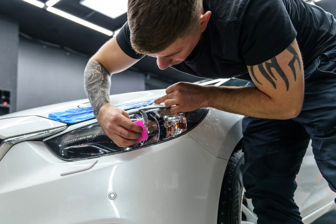 mężczyzna poleruje lampy w aucie